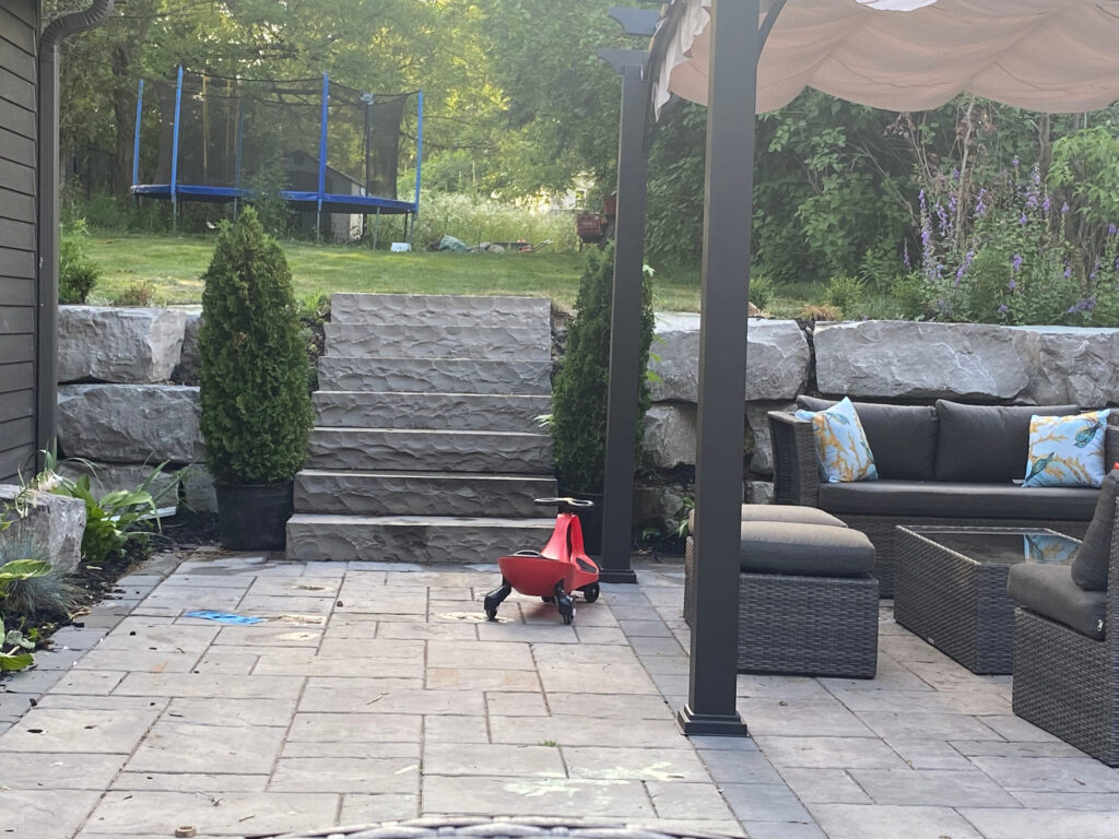 Armour stone steps climbing from a patio to the upper lawn