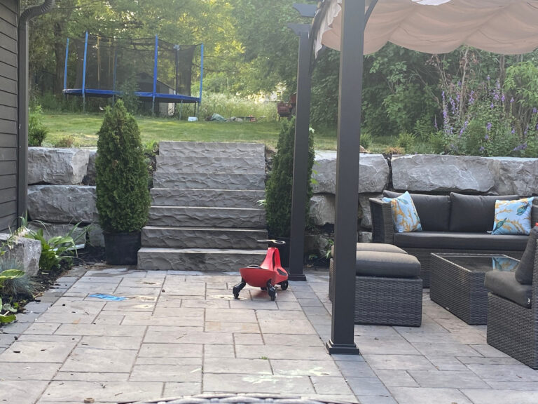 Armour stone steps climbing from a patio to the upper lawn