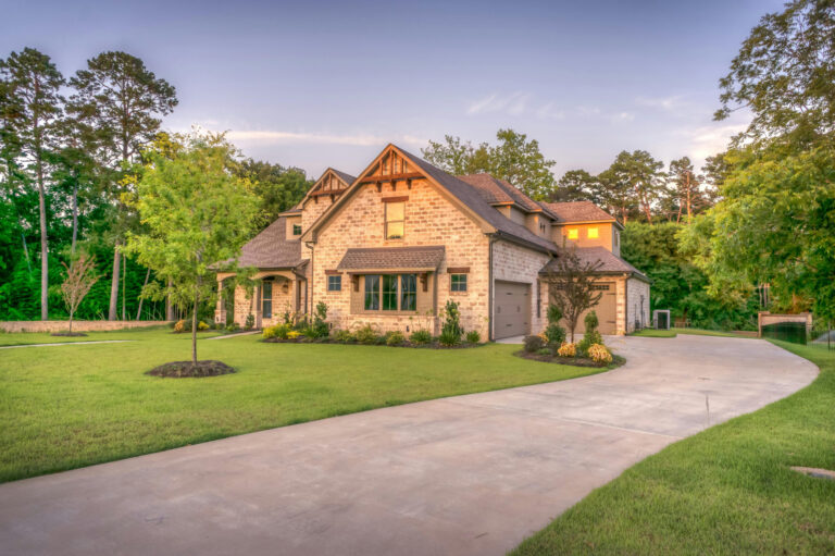 A country home with a long driveway and lawn at golden hour