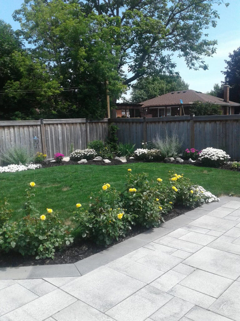 A paver walkway lined with flowering shrubs