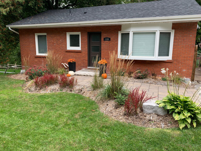 A curved front garden bed with grasses and hostas