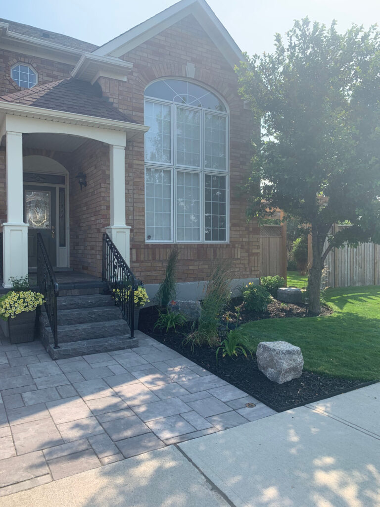 A paver walkway to a front door with fresh planting