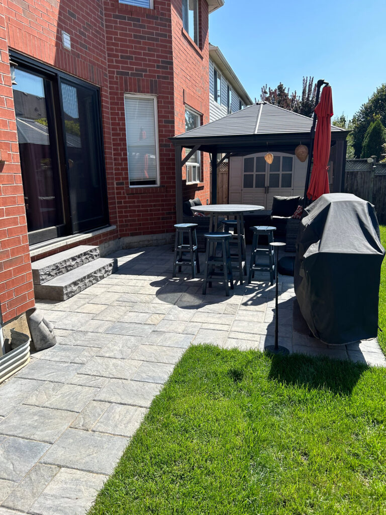 A paver patio with a gazebo and lawn