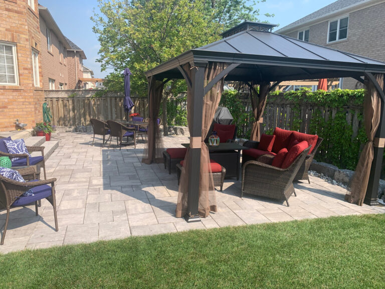 A gazebo with red cushions on a paver patio