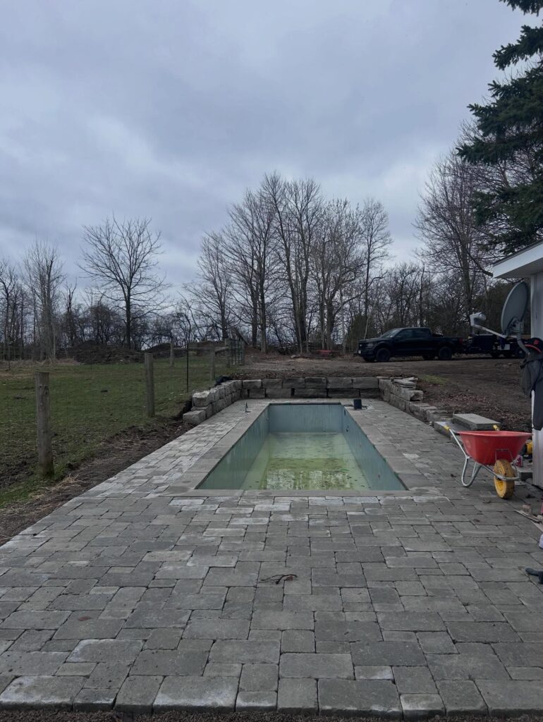 A finished stone pool deck around a long pool