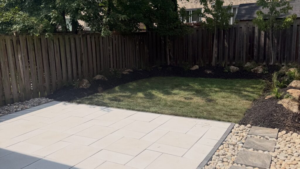 The finished slab patio with lawn and stone edging
