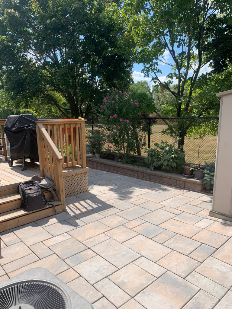 A paver patio beside a deck and stairs