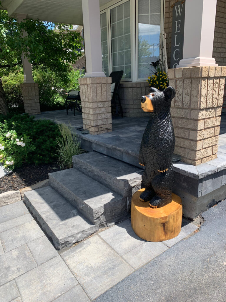 Stone porch steps with a carved bear at the door