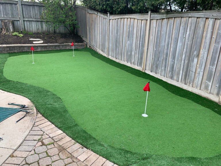 A backyard putting green with flags beside a pool