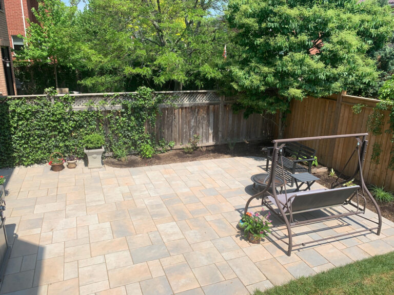 A paver patio with a garden swing
