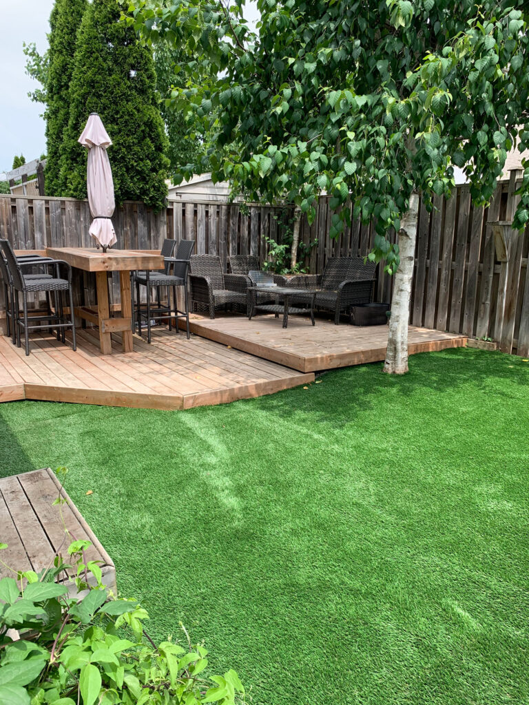 A lawn of artificial turf below a dining deck