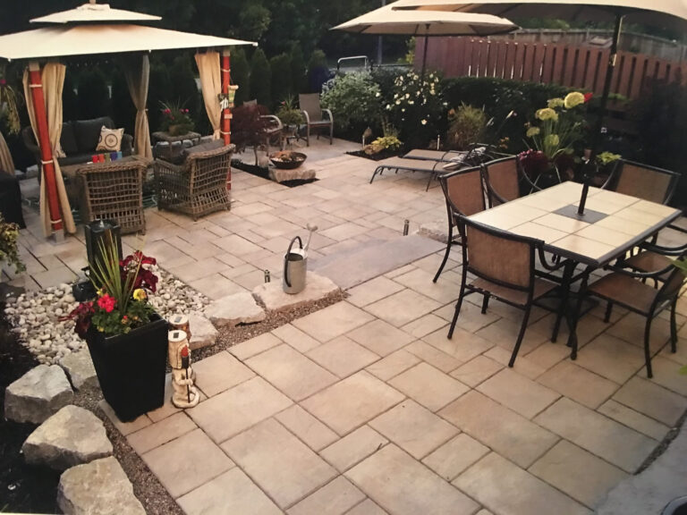 A stone patio with dining set and umbrellas